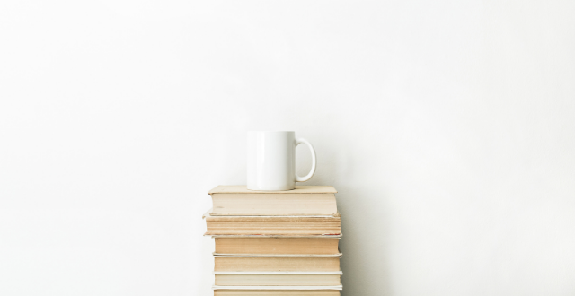 Minimalist stack of books with a white wall and minimal clutter