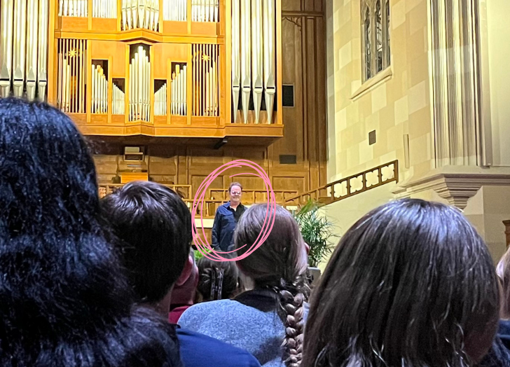 An audience watches a Rainn Wilson, Dwight from the Office, circled in pink, is highlighted as the focal point of the event. This image represents creative content, online business, and personal growth, themes central to Deanna Seymour's approach to content creation.